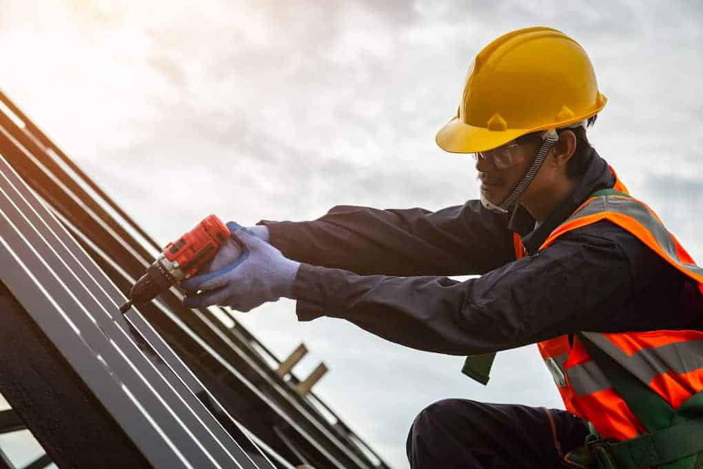 male roofer drilling on roof; roofing industry statistics