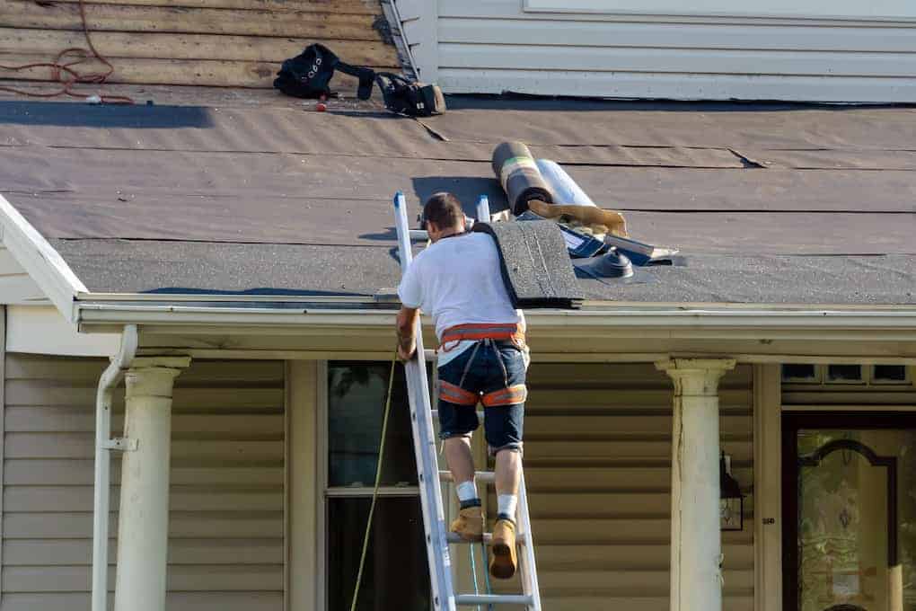 roofer carrying shingles up ladder testing roof shingle weight